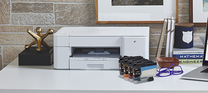 Brother’s MFC-J1205W inkjet printer on a desk, with ink cartridges